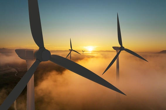 Turbinas eólicas entre niebla al amanecer generando energía limpia.