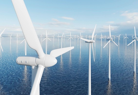Aerogeneradores blancos distribuidos sobre el océano bajo un cielo azul, formando un parque eólico marino de gran escala.