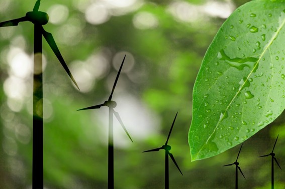 Siluetas de aerogeneradores con fondo verde difuso y una hoja en primer plano con gotas de agua, representando energía renovable y naturaleza.