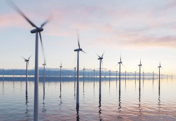 Vista de múltiples turbinas eólicas instaladas sobre el mar, con hélices girando suavemente bajo un cielo claro, representando producción de energía limpia en un entorno acuático.