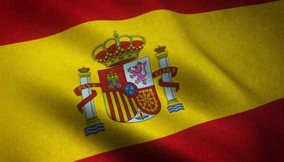 Bandera de España ondeando, con franjas rojas y amarillas y escudo nacional en el centro.